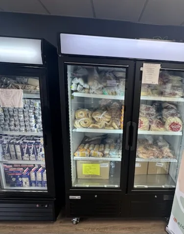 Glass-door fridges holding bagged bread, buns, pastries and packaged baked goods on wire shelves