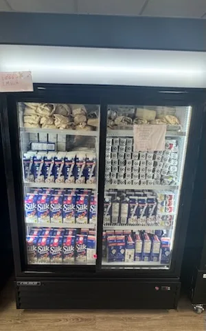 A two-door fridge stocked with cartons of Silk milk, yoghurt, eggs and bagged bread