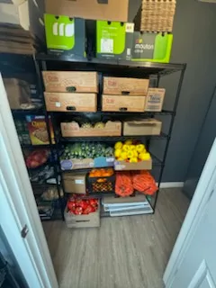 Boxed produce, peppers, lemons and bagged carrots stacked on shelving in the food bank stockroom